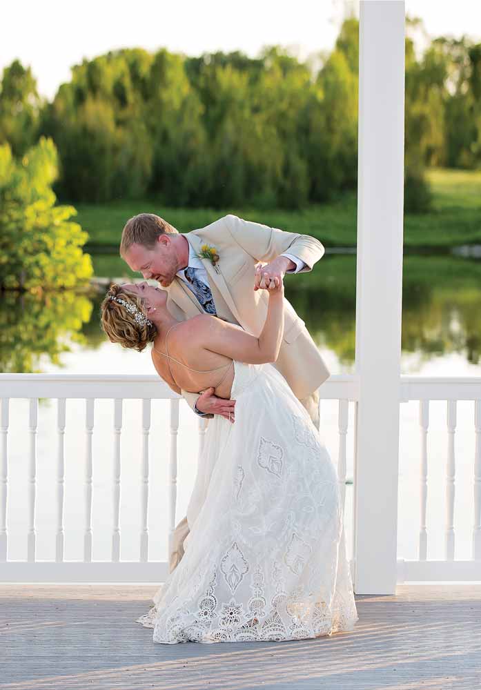 Bride and Groom kissing on the Grand Gazebo with white rail fencing and pond in the background