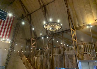 looking up at a wagon wheel chandelier and stairway and balcony in background in the Big Red Barn