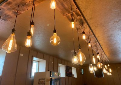 various hanging lights above bar with eclectic display of light bulbs in the Big Red Barn
