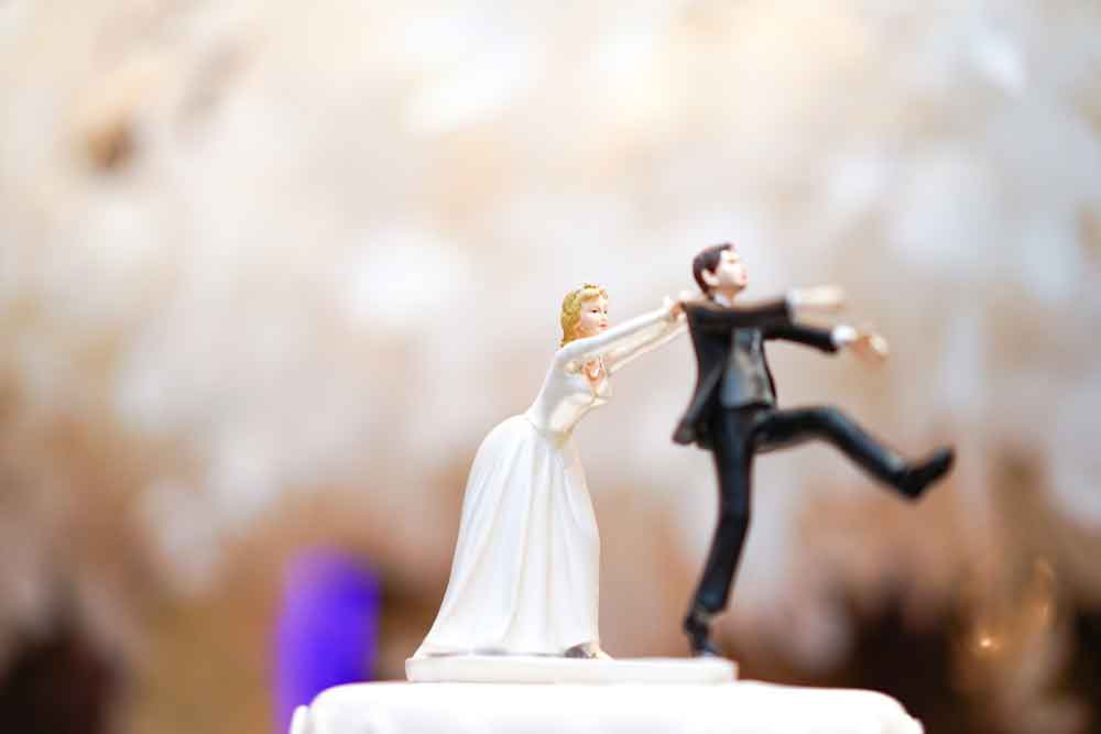 image of cake topper with bride trying to hold on to runaway groom